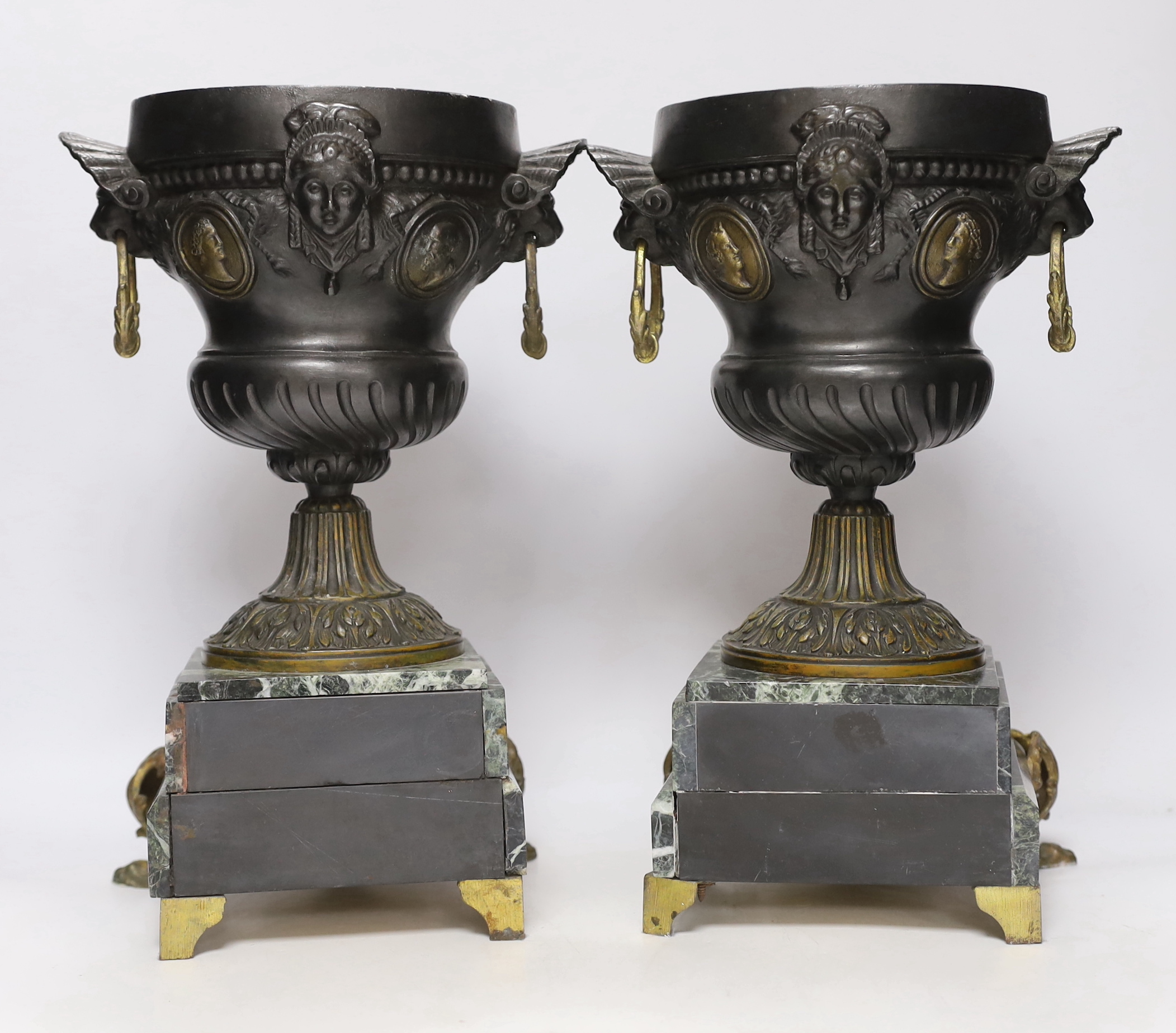 A pair of late 19th century French gilt metal and brown patinated urns, decorated with masks and serpentine plinths, 33cm high
